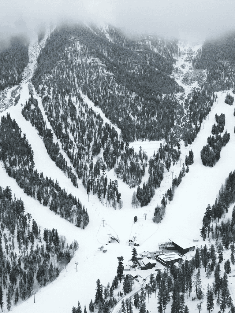Snow-covered mountain ski resort with chair lifts and forested slopes during winter.