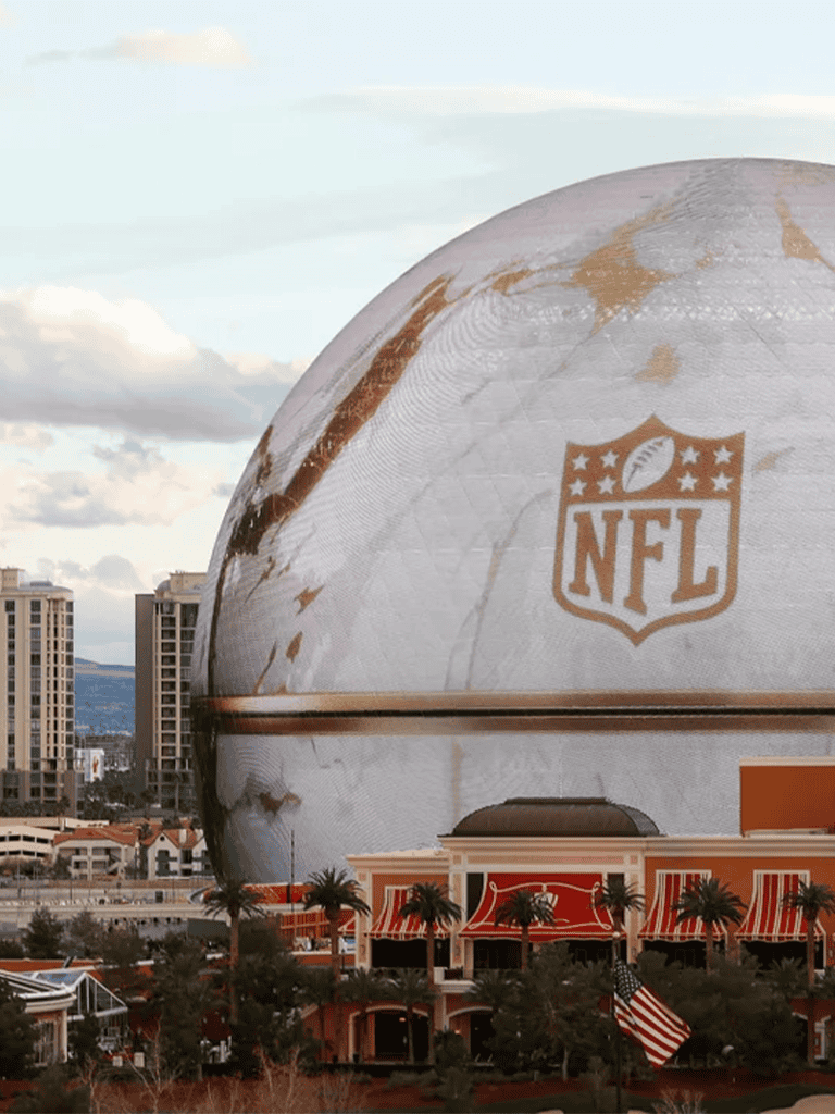 NFL football-themed stadium shaped like a giant football apparatus, located in a vibrant cityscape with palm trees.
