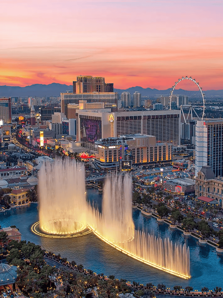 Colorful cityscape of Las Vegas at sunset with the Bellagio Fountains in full display, vibrant lights and iconic skyline.