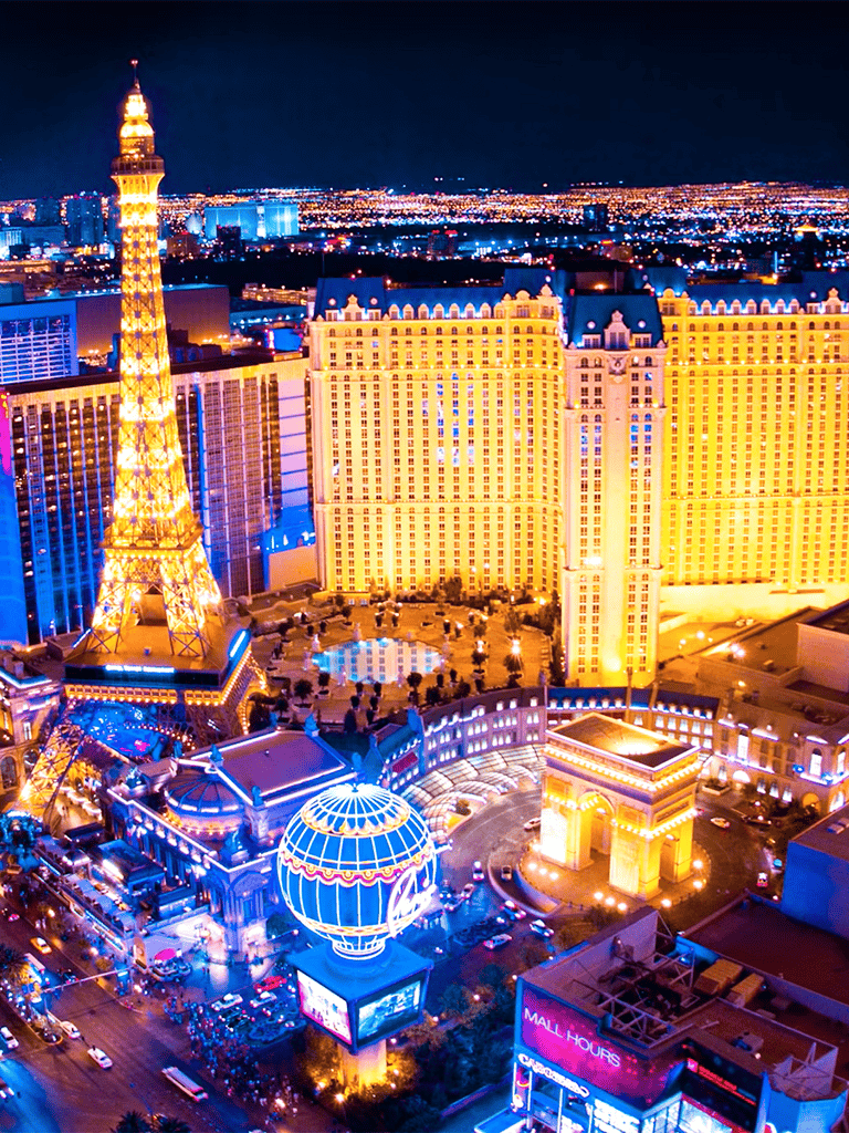 Brightly lit Las Vegas Strip at night featuring the Paris Las Vegas Hotel and Eiffel Tower replica.