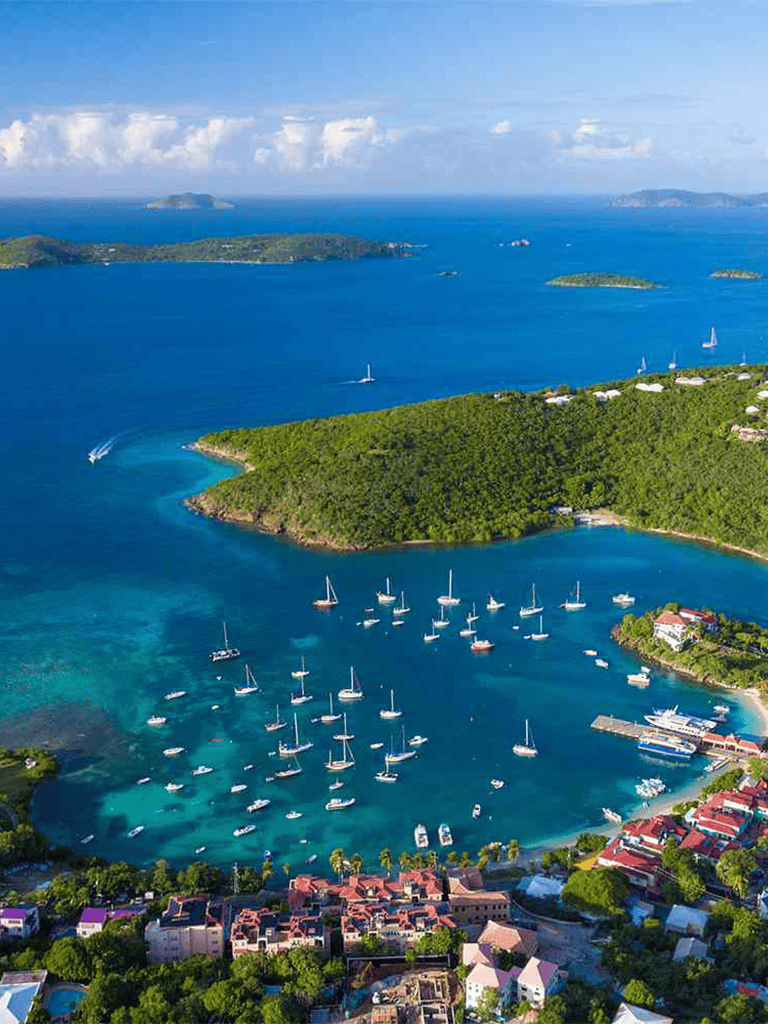 Serene harbor with sailboats, lush islands, and coastal town, stunning views of turquoise waters and tropical landscape.