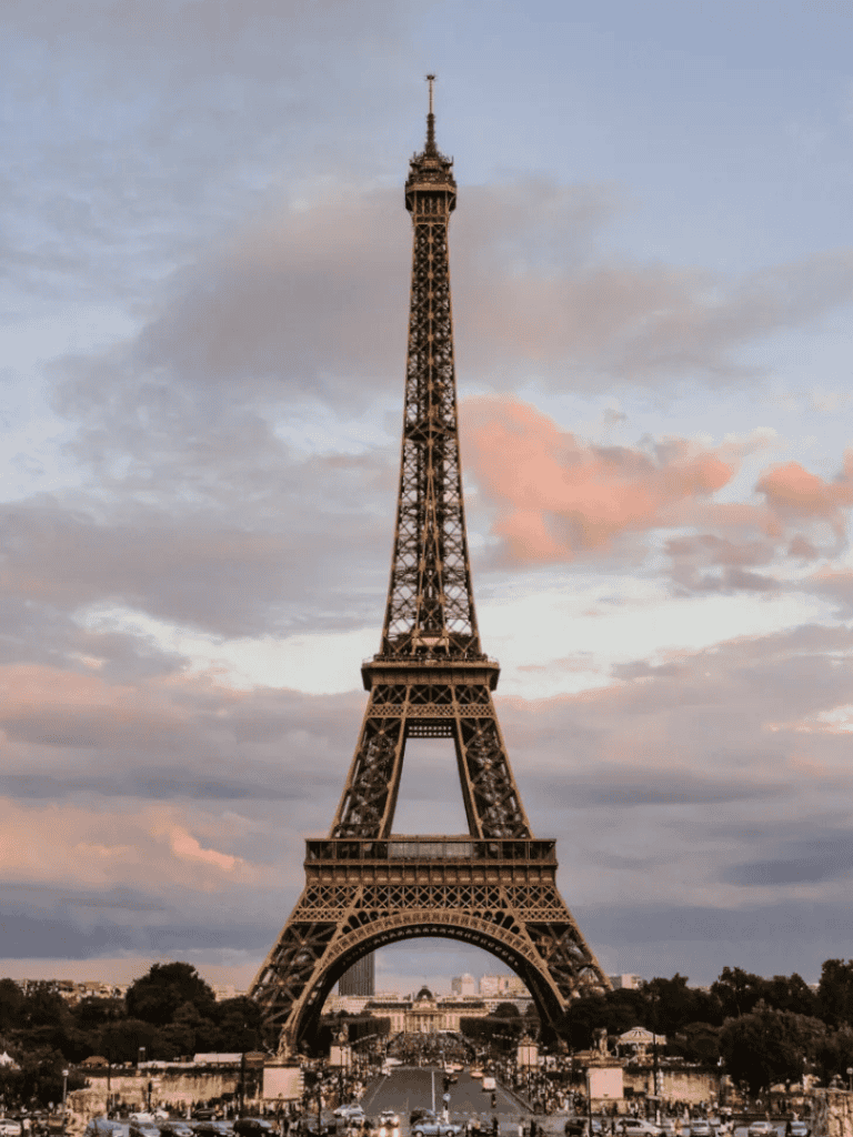 Eiffel Tower in Paris at sunset with cloudy sky and cityscape view.