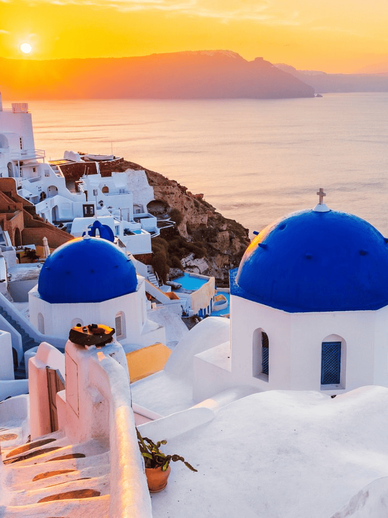 1. Beautiful Santorini sunset with white-washed buildings and blue domes, Greece travel destination.