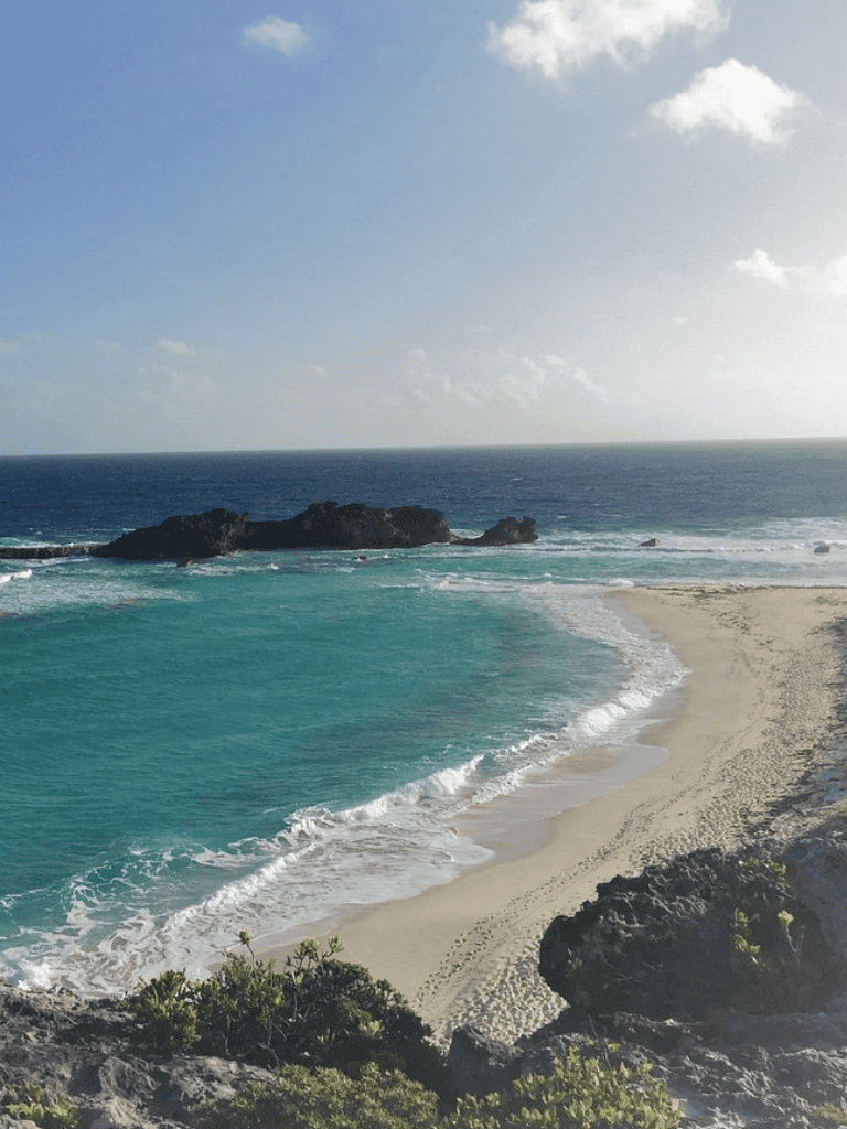 Serene beach with turquoise waters and rocky formations under a clear blue sky.