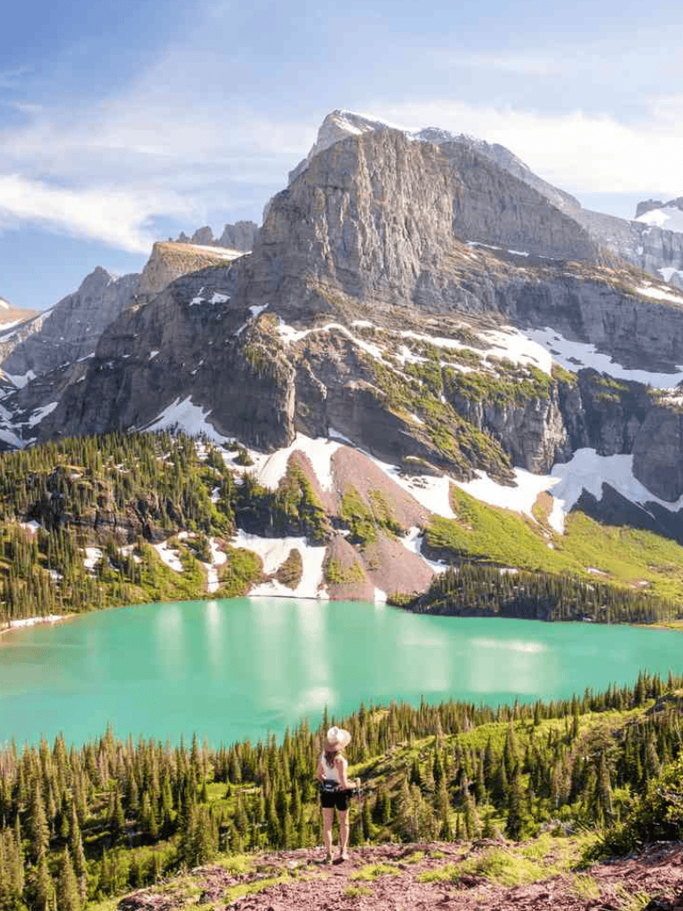 Serene mountain lake with snow-capped peaks and lush evergreen forest, perfect for outdoor adventure and nature photography.