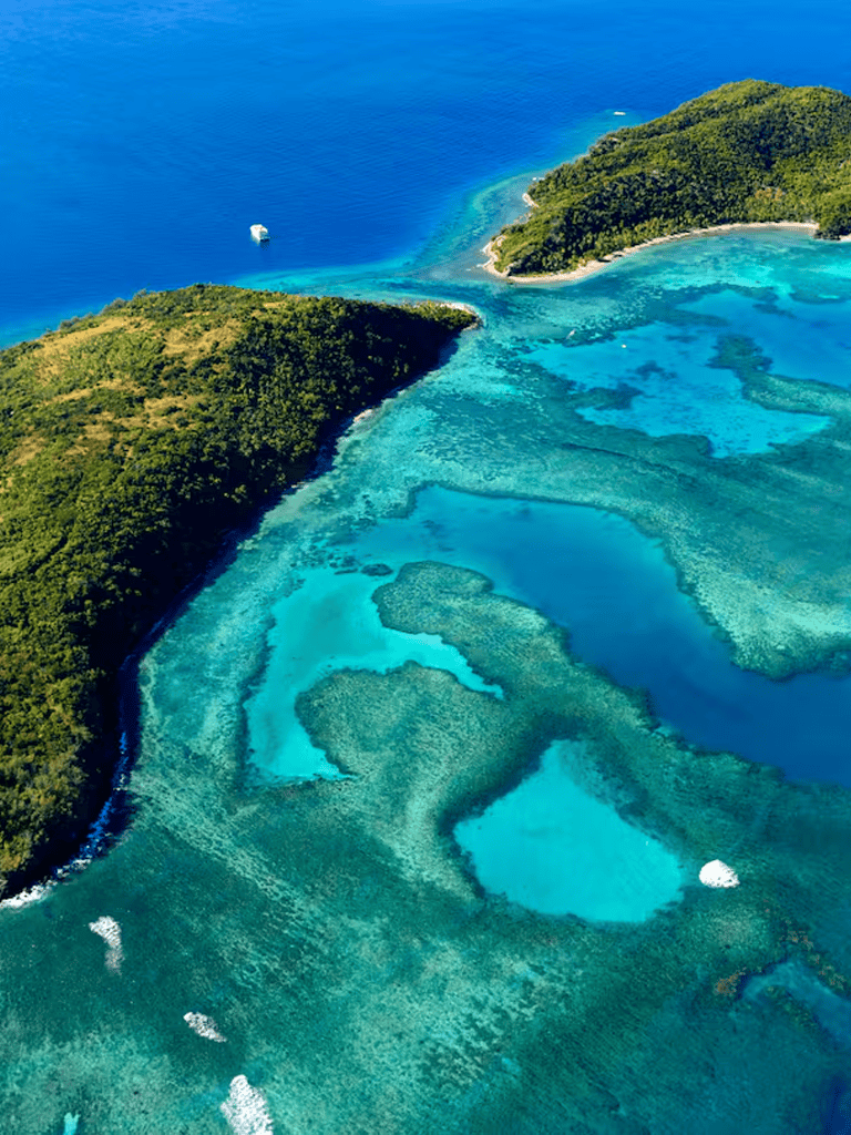 Vivid aerial view of tropical island with clear turquoise waters and coral reefs, perfect for travel and adventure planning.