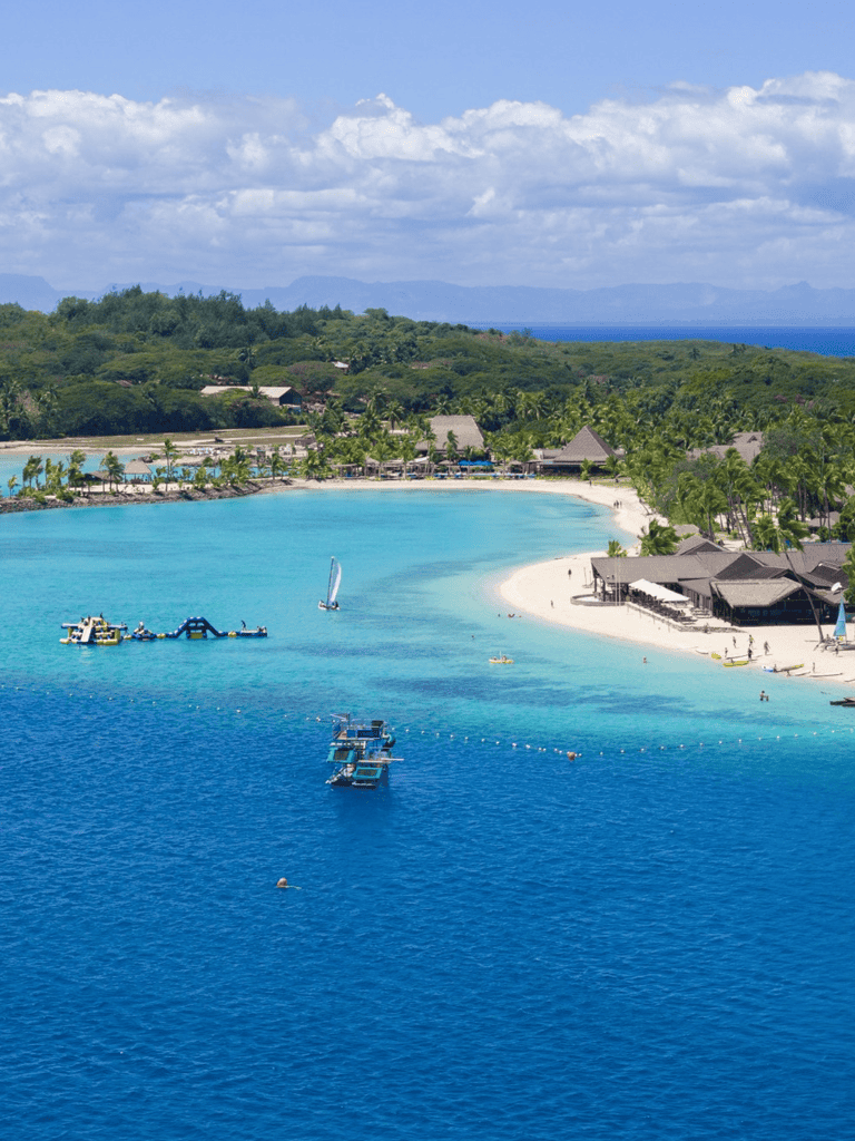 Stunning Caribbean beach with clear turquoise waters, luxury resorts, and sailing boats. Perfect vacation destination for relaxation and fun.