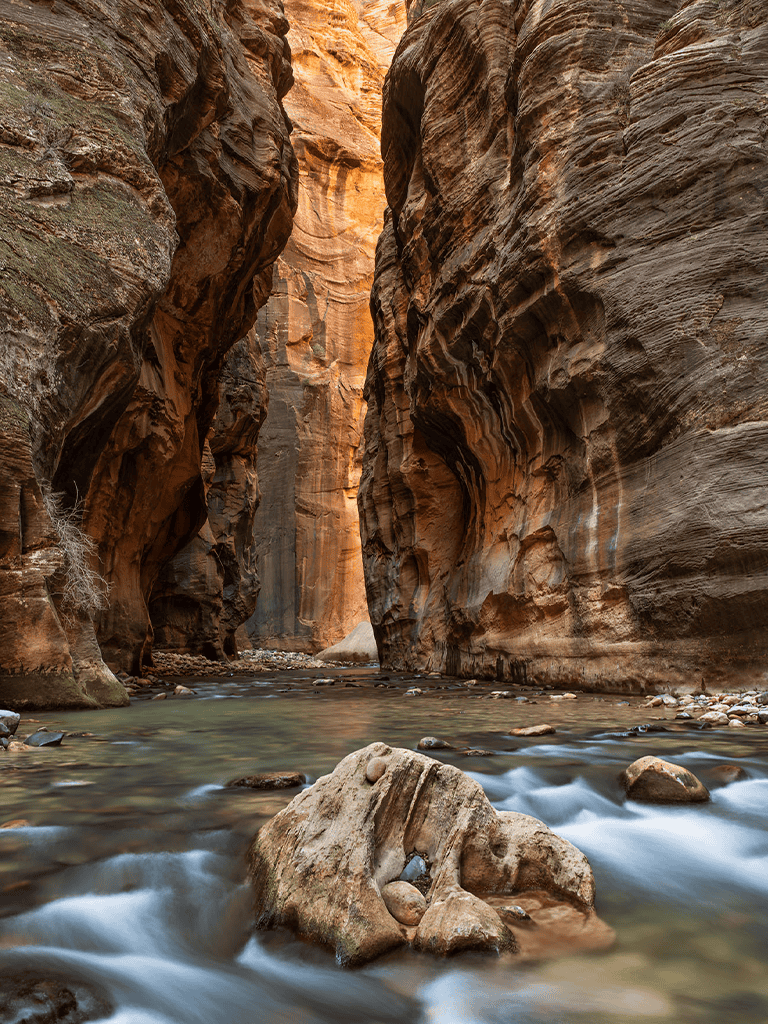 Majestic canyon with towering layered rock walls and a flowing river, creating a stunning natural landscape.