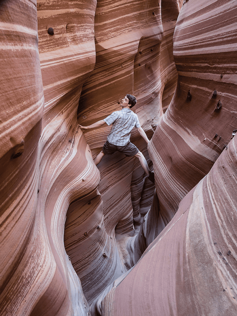 Vivid slot canyon with sandstone walls and a person exploring narrow passageways.