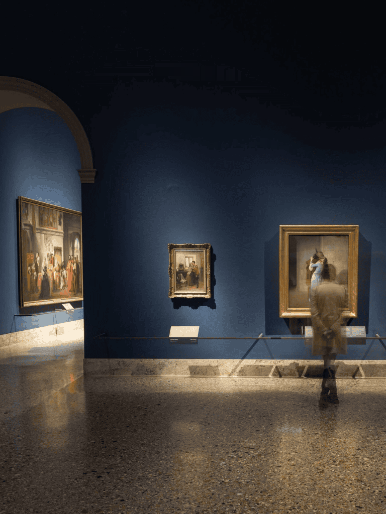 Elegant art gallery interior with classic paintings and subdued lighting.