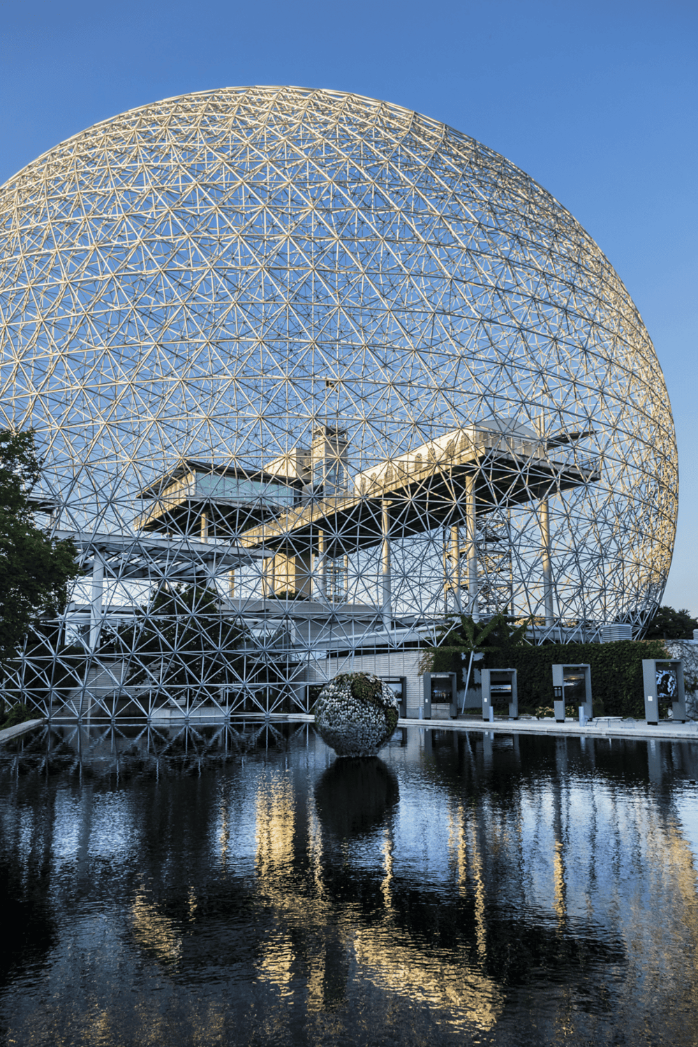 Modern geodesic dome structure with reflective water feature, architectural innovation.