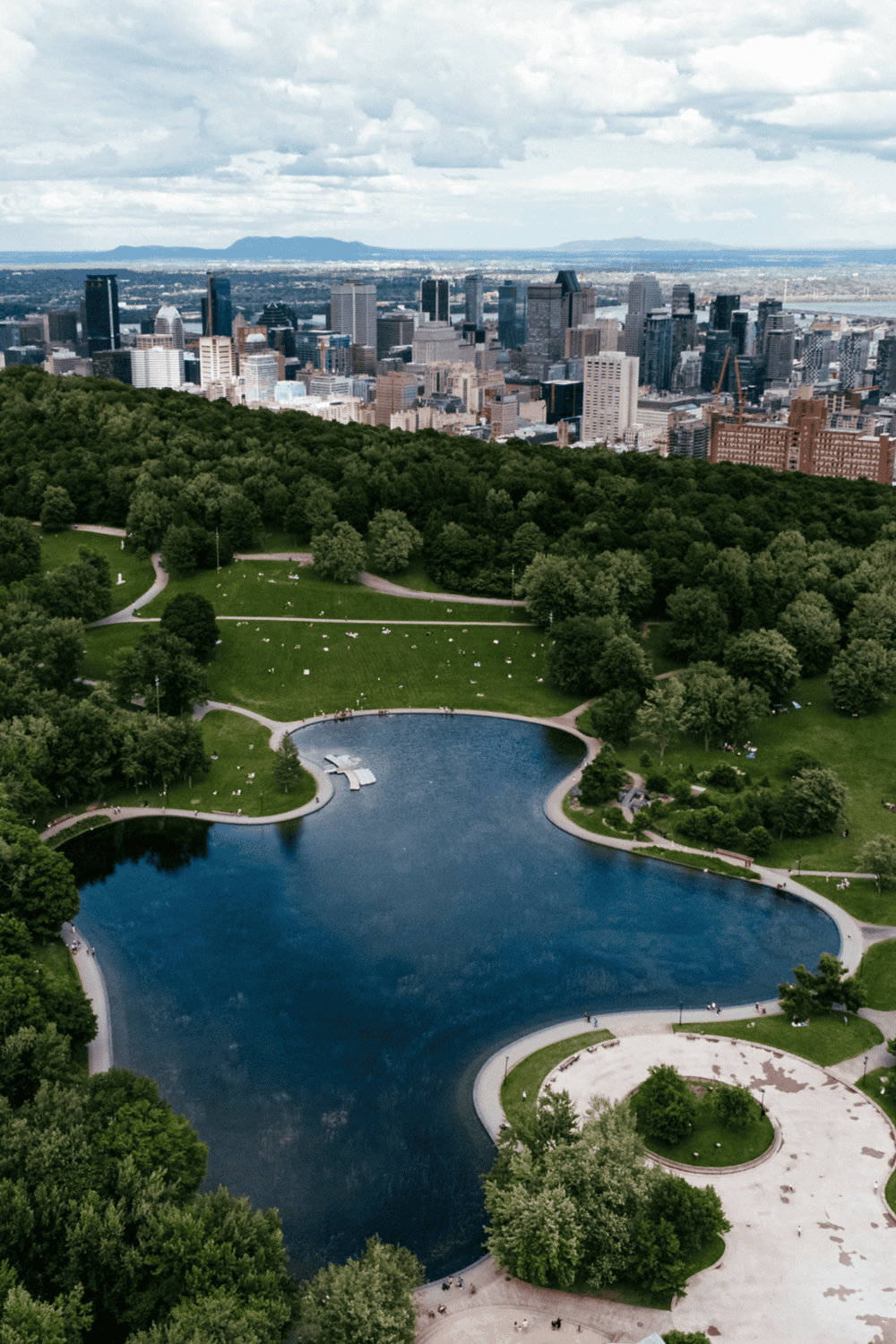 Aerial view of Central Park with city skyline, green trees, and water bodies, highlighting urban park and NYC attractions.