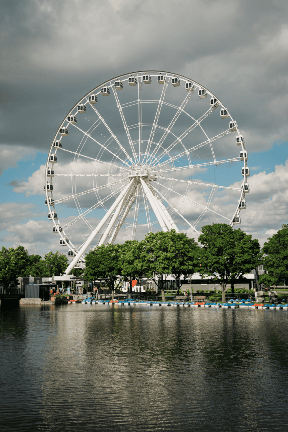1. Large Ferris wheel at waterfront with trees and cloudy sky.