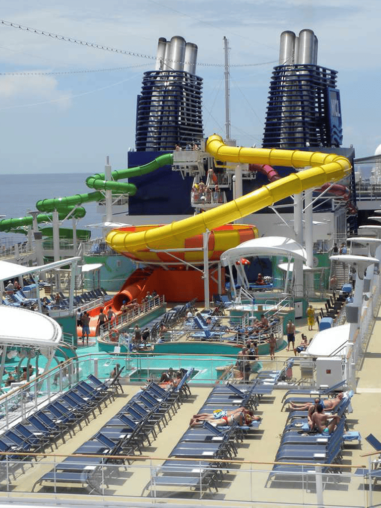 Colorful cruise ship water slides with pools and lounge chairs on deck, popular for vacation leisure.