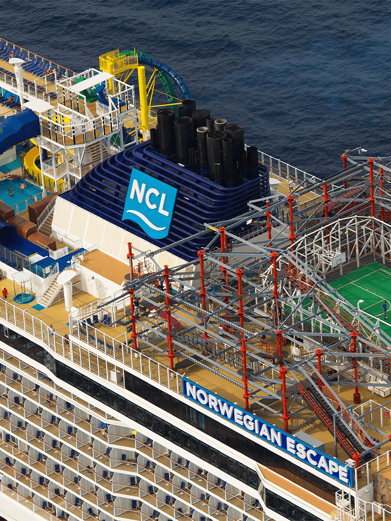 Colorful cruise ship with water slides and entertainment areas at sea.