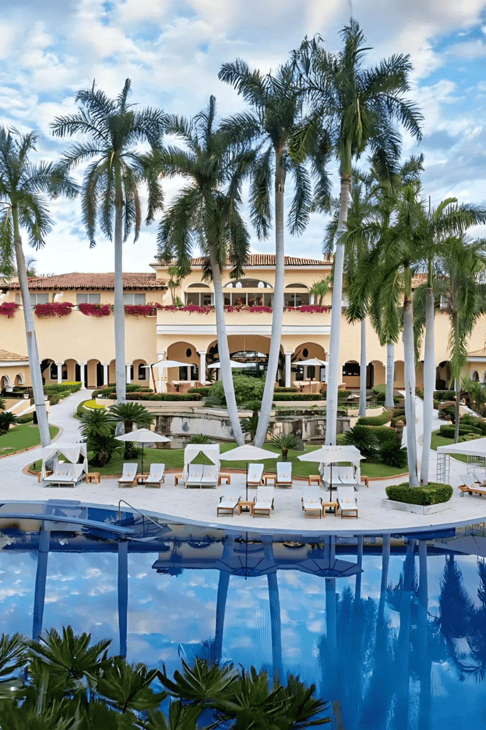 Luxurious tropical resort with swimming pool and palm trees, perfect for vacation relaxation.
