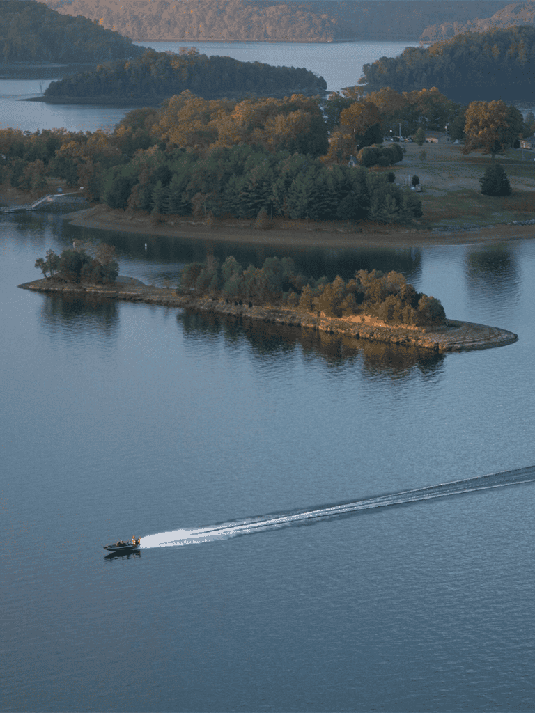 Serene lake with lush island and boat cruising through calm water in a scenic outdoor landscape.