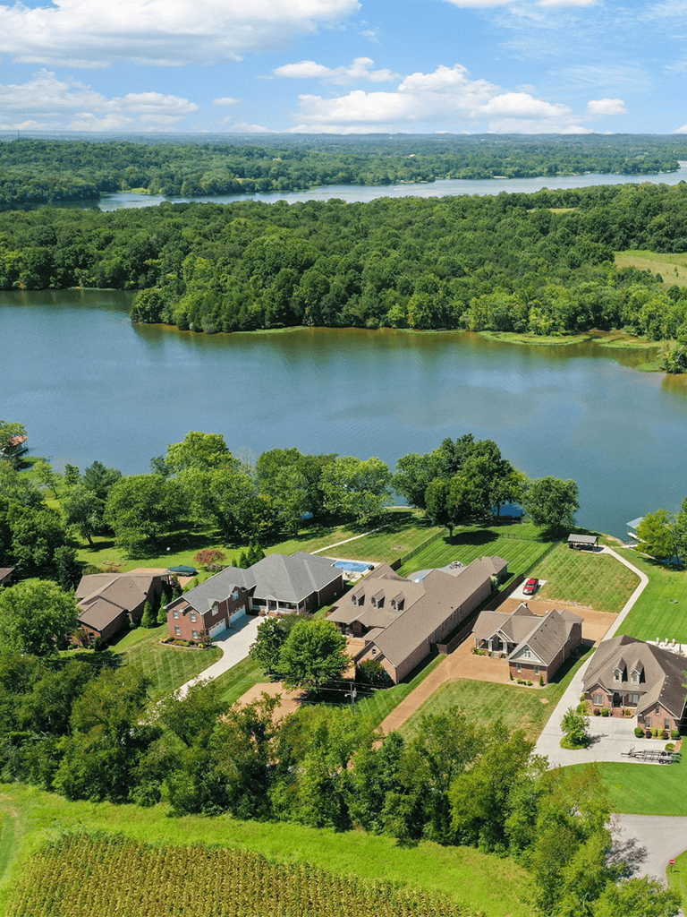 Serene lakeside residential community surrounded by lush green forests and scenic water views.