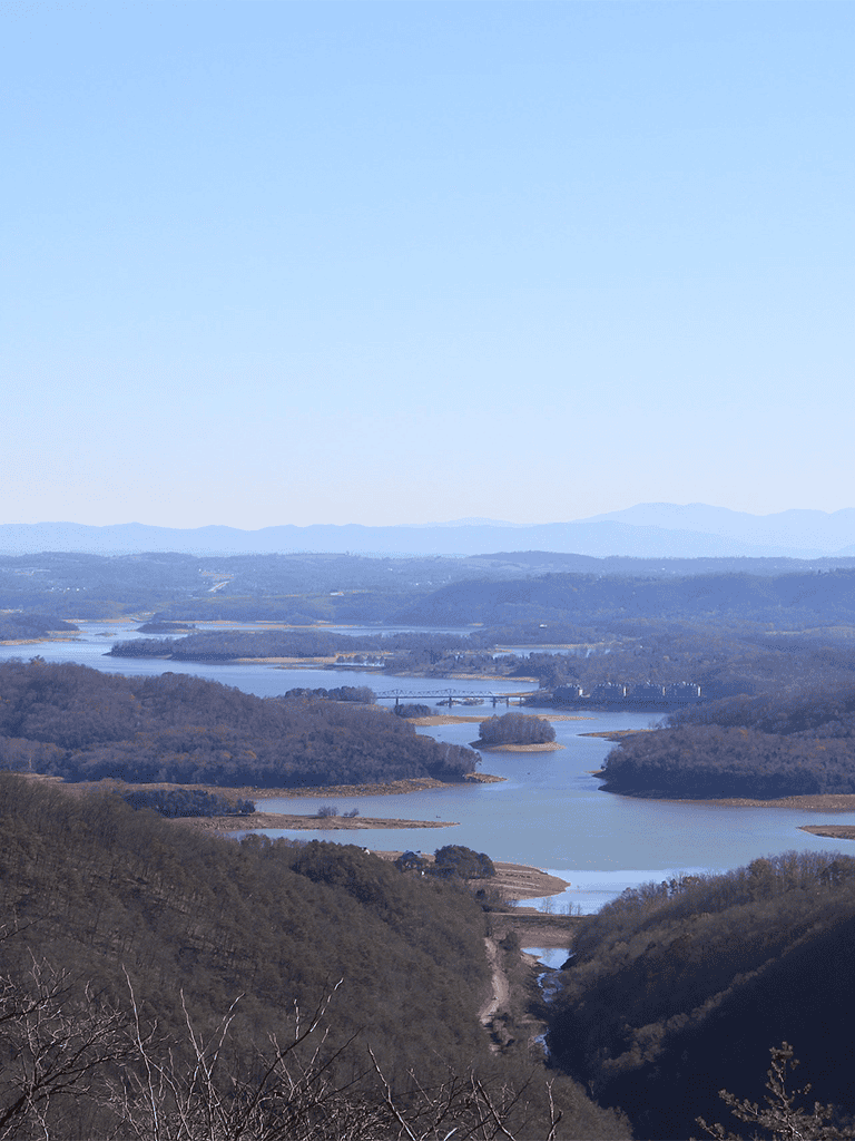 Vast landscape of interconnected lakes and rolling hills with distant mountain ranges.