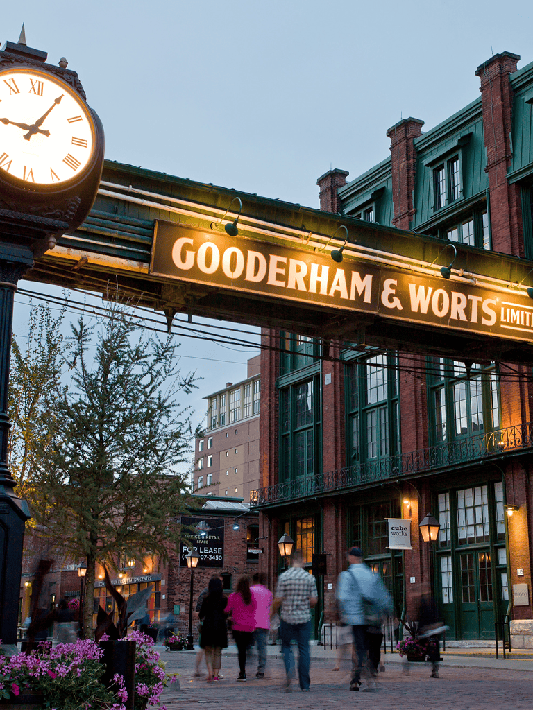 Historic brick building with illuminated "Gooderham & Worts" sign in Toronto's Distillery District at dusk.