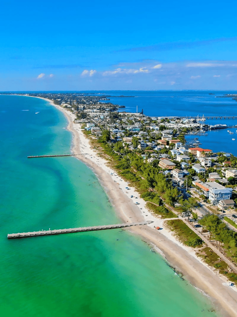 Aerial view of coastal town with beaches, ocean, and marina, perfect for travel planning and direction services.