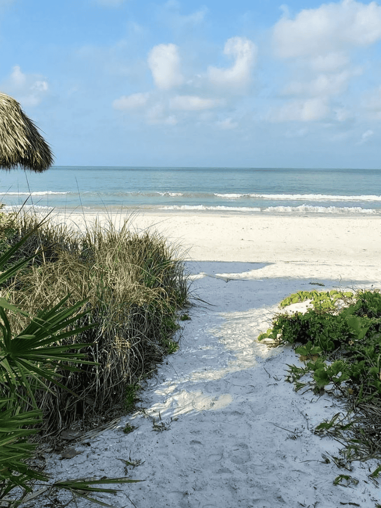 Relaxing beach scene with white sand, ocean waves, and blue sky, perfect for a travel destination or vacation planning.