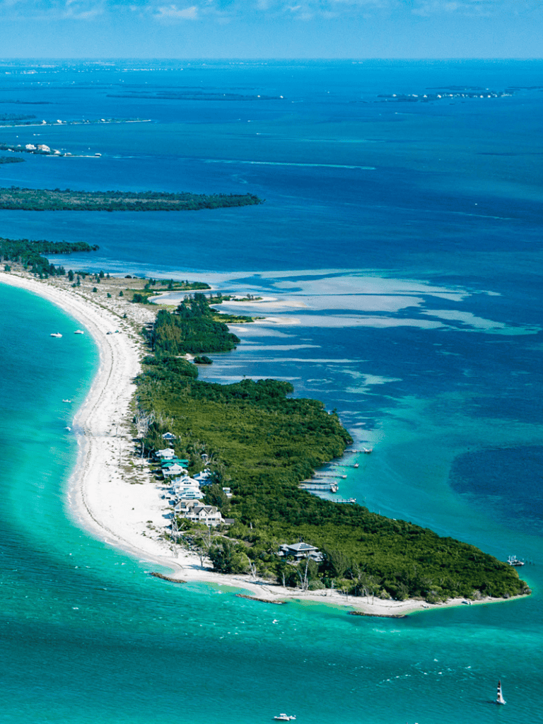 Aerial view of a tropical island with white sandy beaches and lush greenery, surrounded by vibrant blue ocean waters.