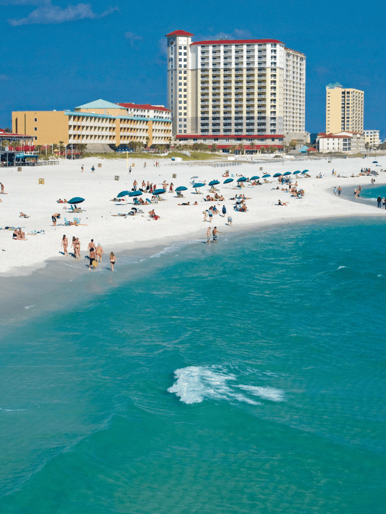 Beach with umbrellas and hotel buildings in the background, sunny day, ocean view, popular vacation destination.