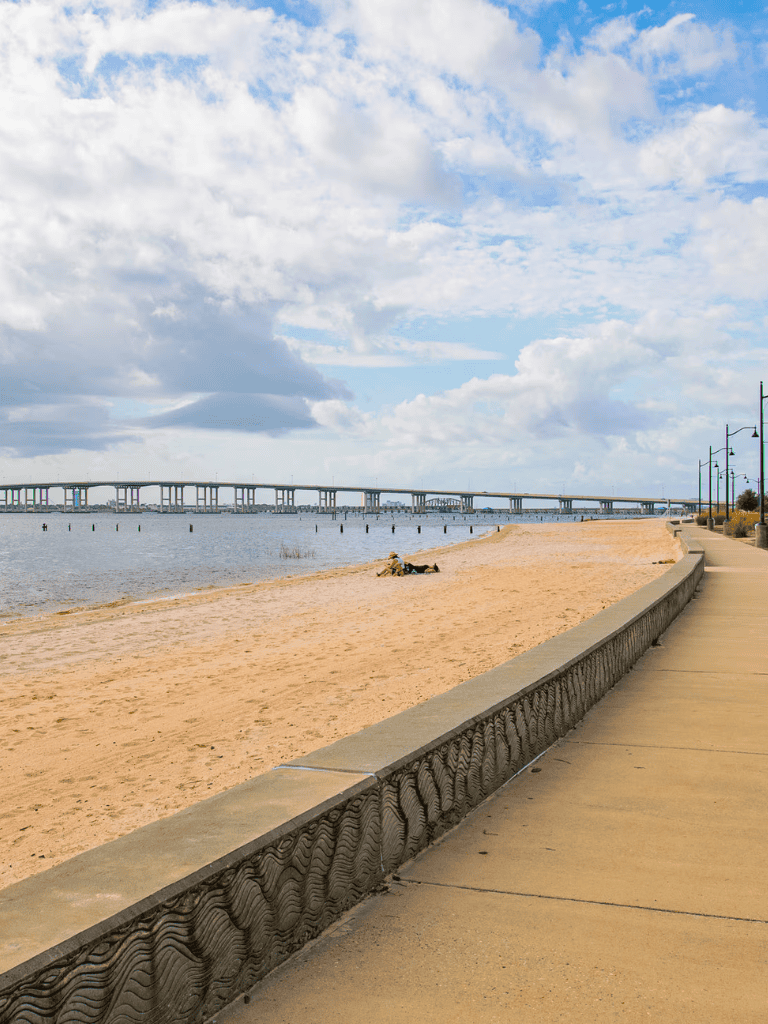Relaxing beach scene with sandy shoreline and scenic bridge over water, perfect for coastal explorations and seaside activities.