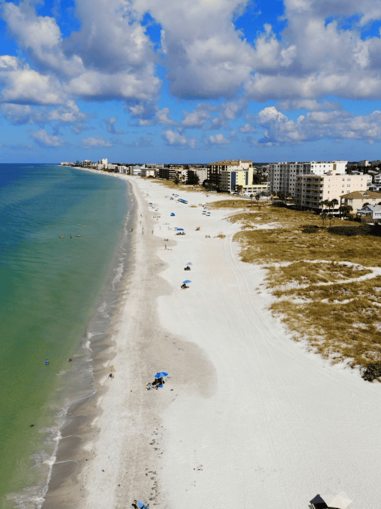 Serene beach scene with white sand, blue umbrellas, and ocean view, perfect for restful seaside vacations.