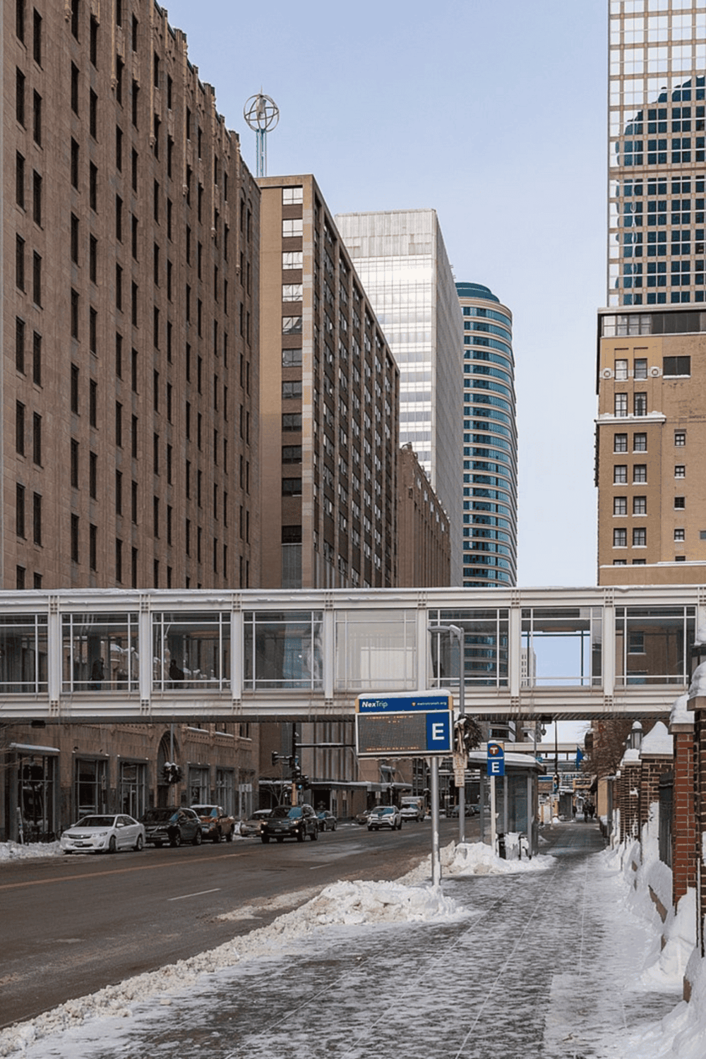 Modern urban cityscape with skyscrapers and transit station in snow-covered streets.
