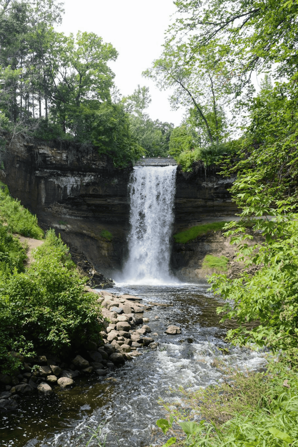 Serene waterfall surrounded by lush greenery at QuestForDirections, offering scenic views and outdoor exploration opportunities.