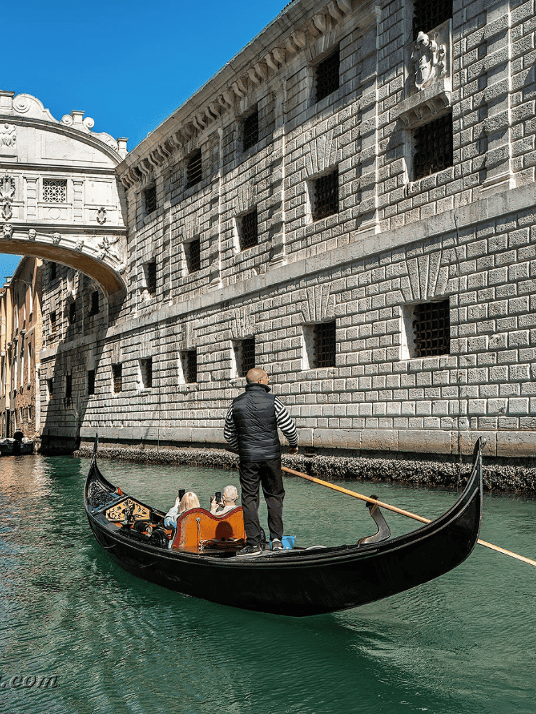 Gondola ride in Venice near historic stone building with ornate architecture.