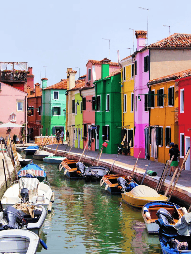 Colorful Venetian Canal with Boats, Italy travel destination image, vibrant cityscape, scenic waterfront, QuestForDirections SEO photo.