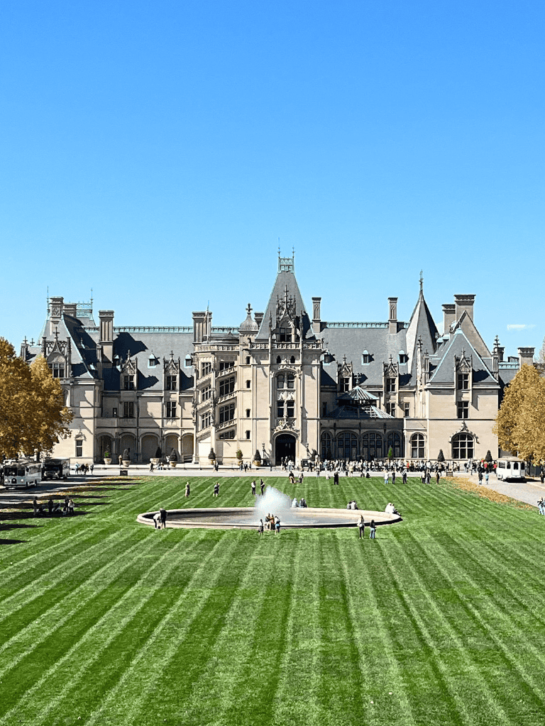 Luxurious castle hotel exterior with lush green lawn and fountain, perfect for travel destinations and sightseeing.