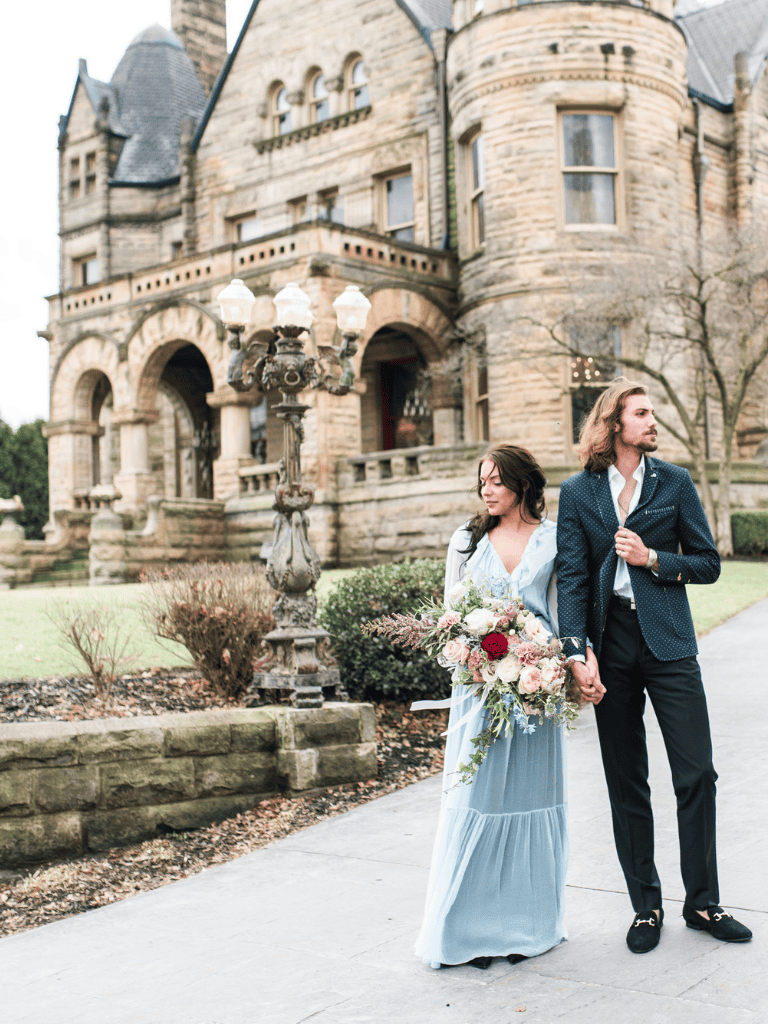Elegant couple standing near historic castle for wedding photography.