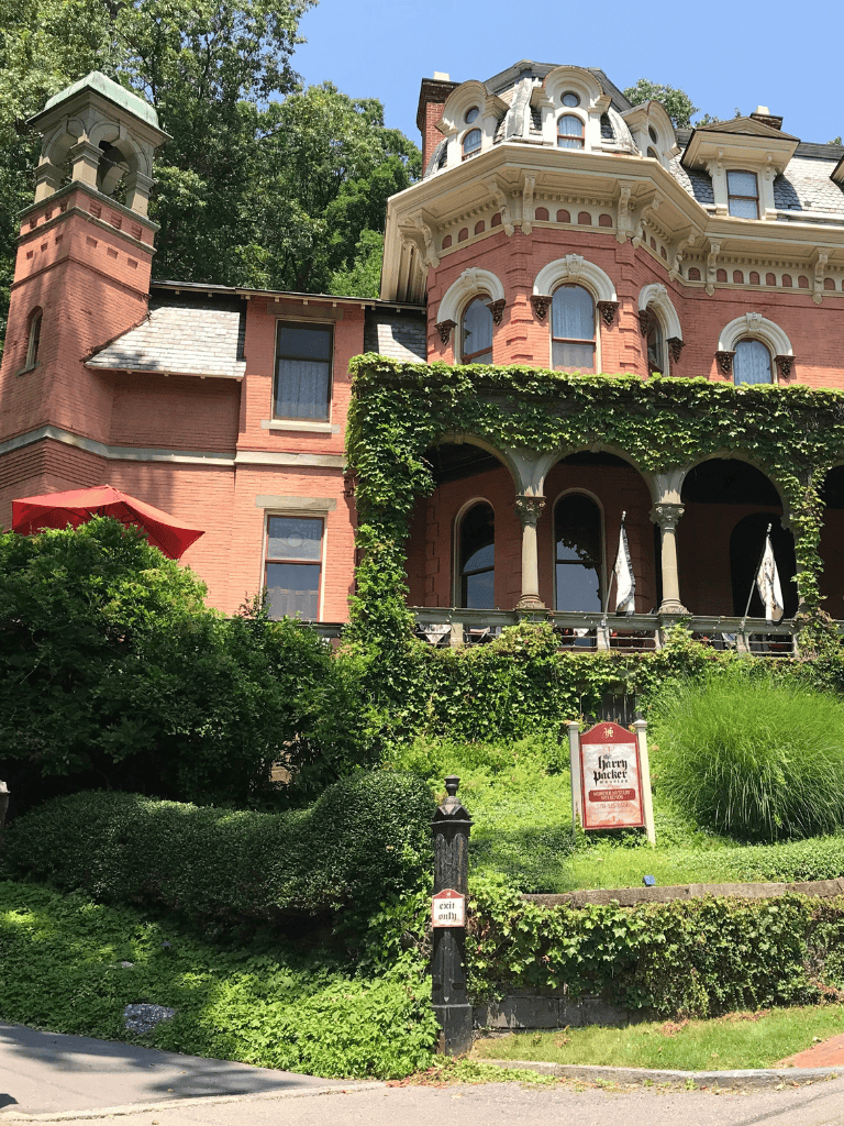 Elegant Victorian mansion with ivy-covered facade and lush landscaped garden.