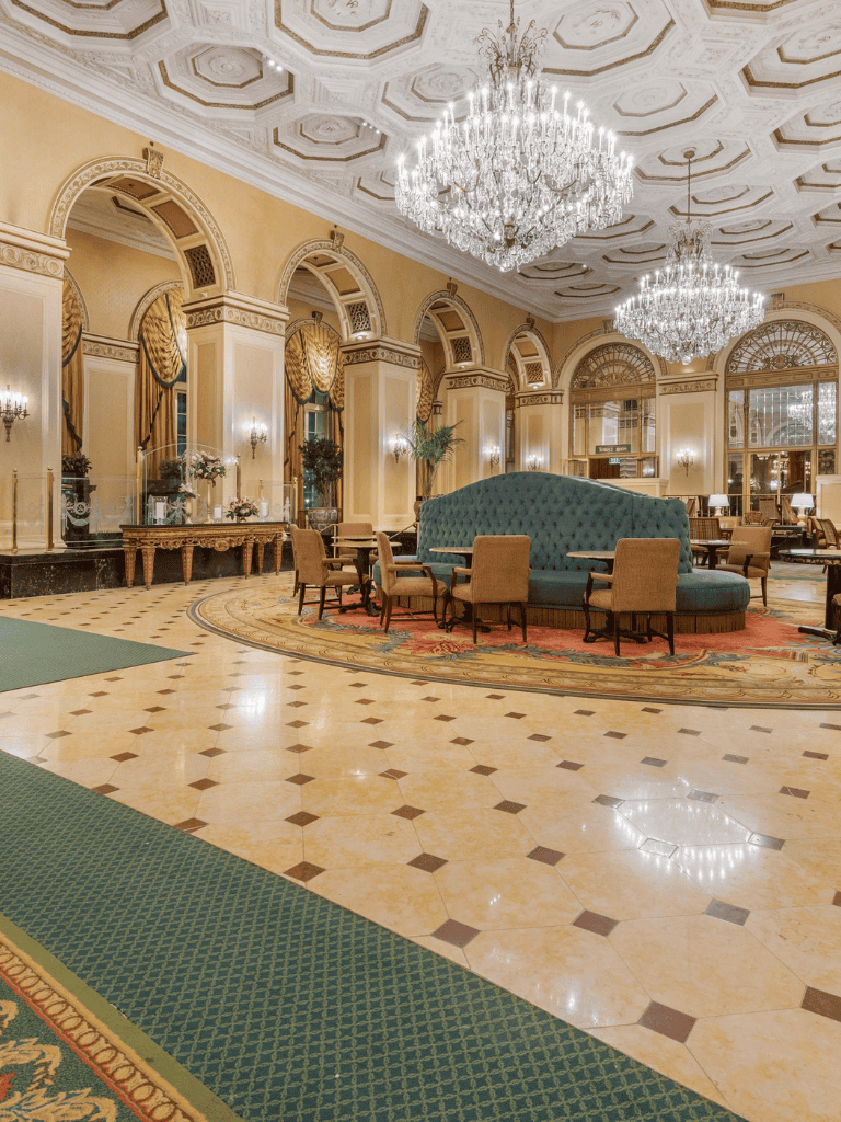 Elegant hotel lobby with chandeliers, ornate decor, and luxurious seating areas for guests.