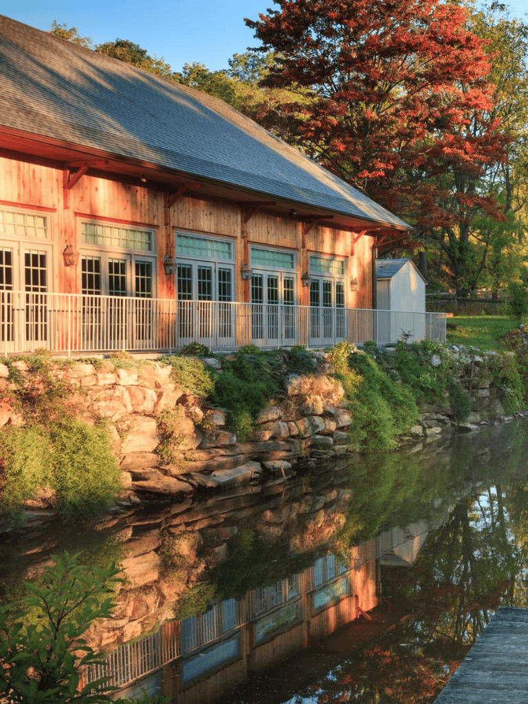 Tranquil lakeside cabin with colorful autumn trees and reflections in water, perfect for nature retreats.