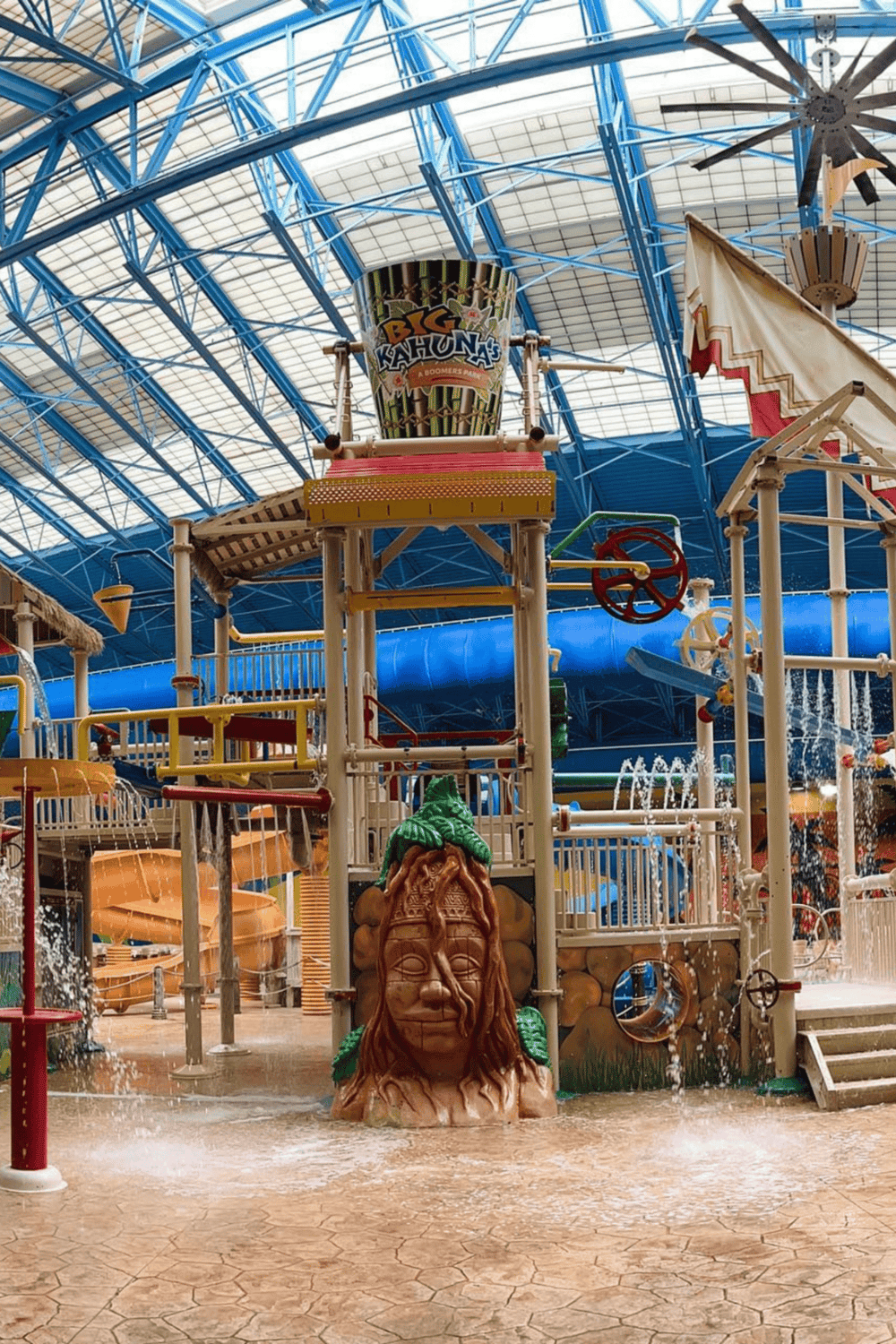 Vibrant indoor water park with water slides and attractions under a glass dome ceiling.