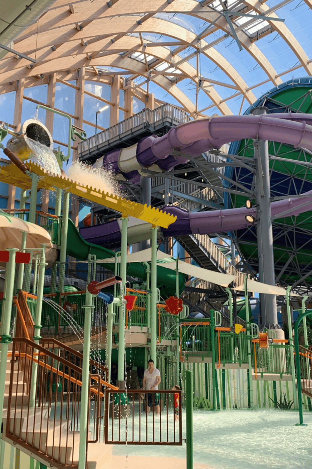 Water park with colorful slides and water attractions inside a wooden dome structure.