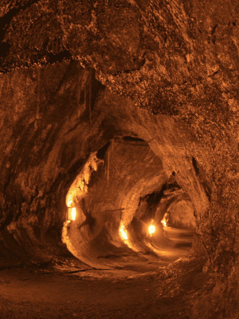 Underground cave tunnel illuminated by warm lights, adventurous exploration site, natural rock formations.