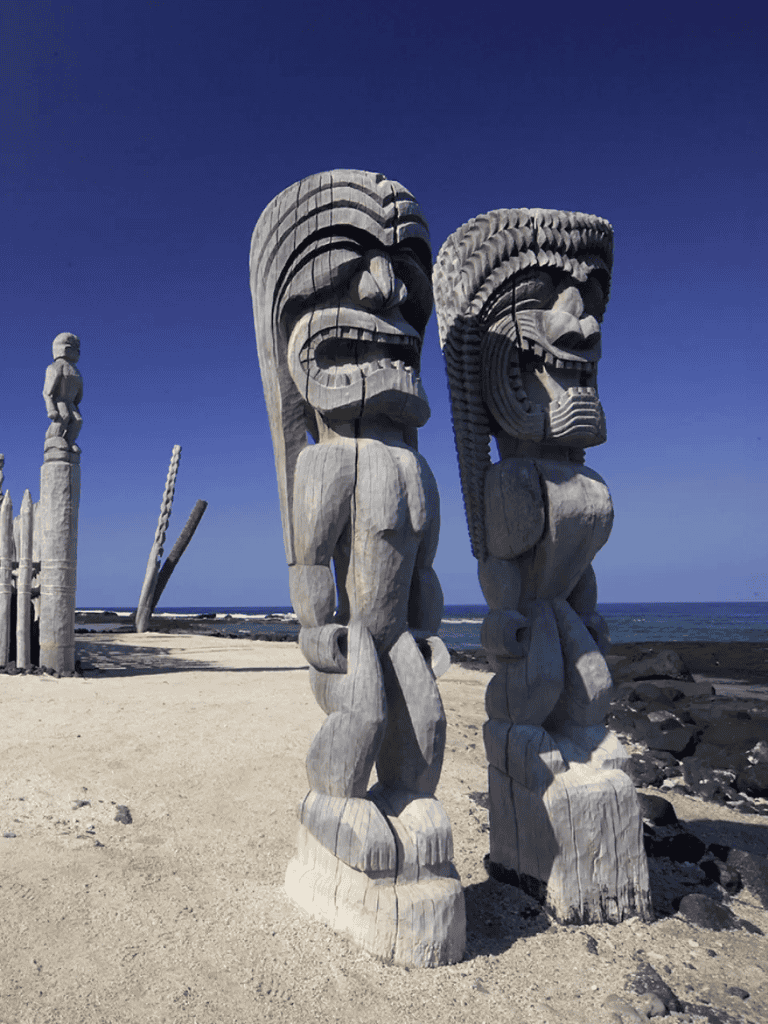 Ancient coastal carved wooden Tiki statues at the beach in Hawaii.