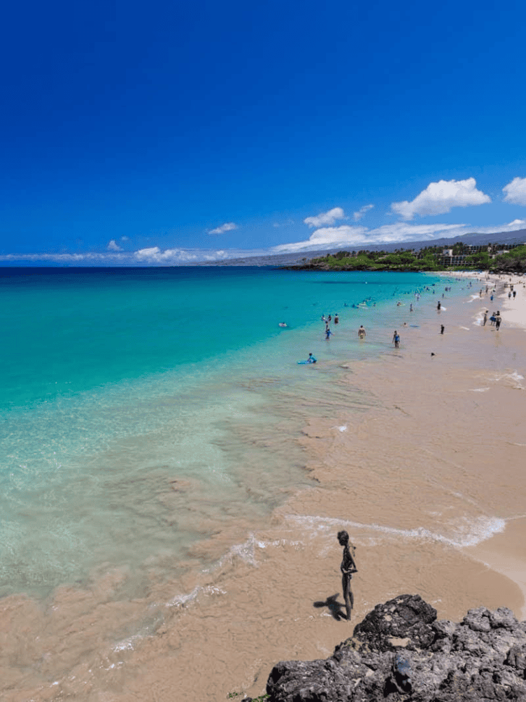 Sunny beach with turquoise waters and people enjoying the summer sun.