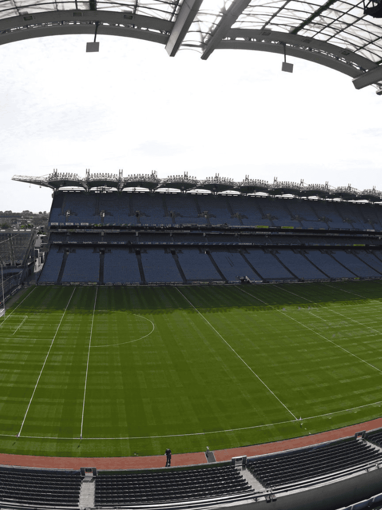 Aerial view of a professional football stadium with green field and empty blue seats.