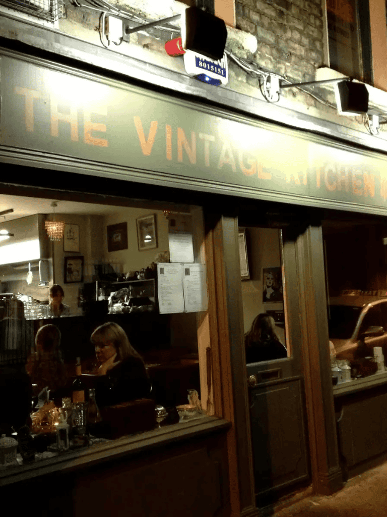 Cozy vintage kitchen restaurant interior with customers dining and staff working, inviting atmosphere for a unique culinary experience.