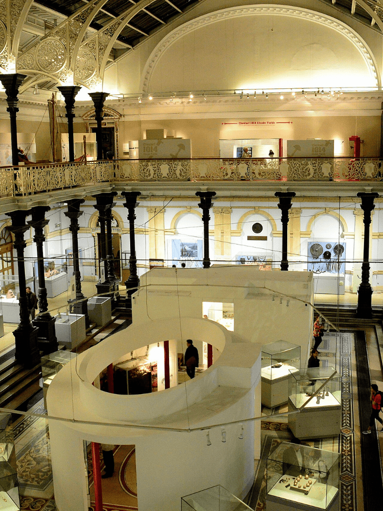 Brightly lit interior of Museum of Fine Arts with ornate architecture and display cases showcasing art pieces.