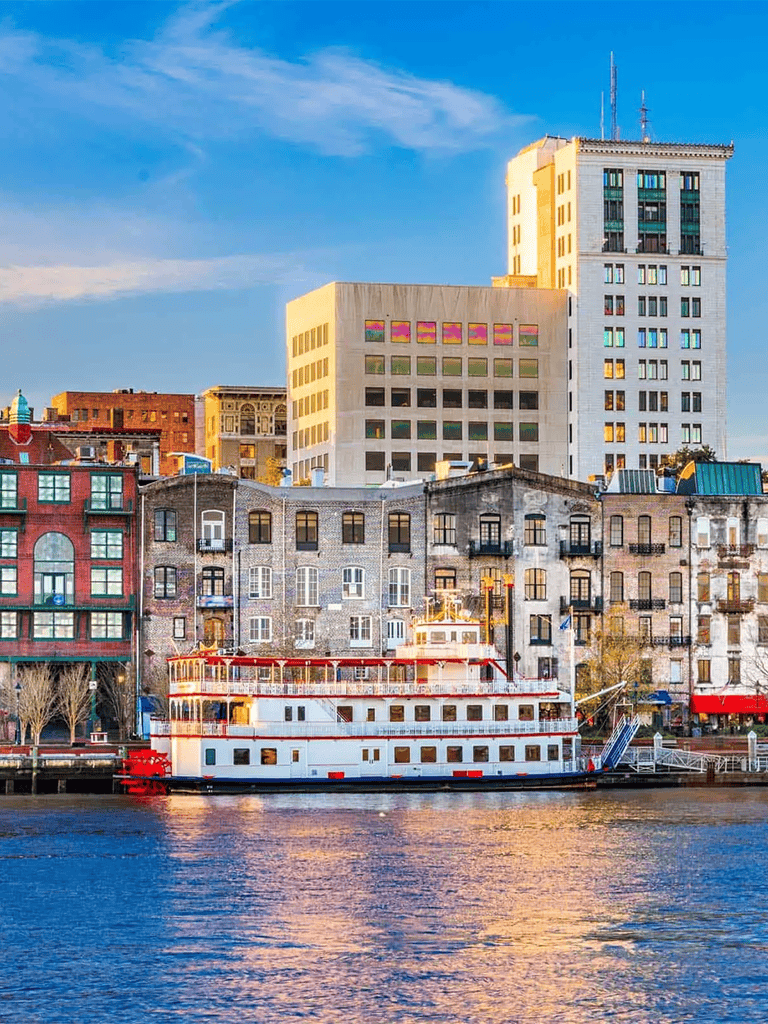 Colorful city buildings and a boat along a waterfront at sunset in urban setting.