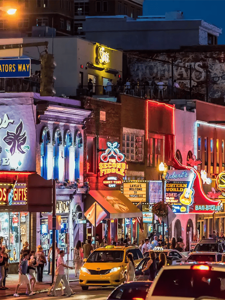 Vibrant Nashville street scene illuminated with neon signs, bustling nightlife, and lively crowd.