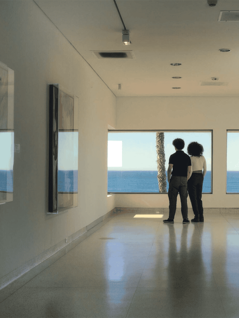 1. Two people looking out at the ocean from a modern indoor space.